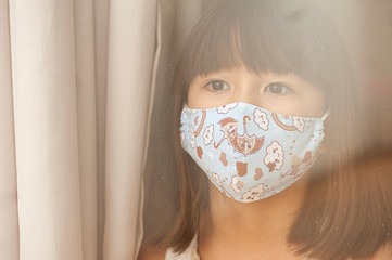 .New normal. Asian-looking girl wearing a mask to protect herself from Covid-19 or a corona virus...