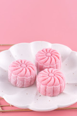 Colorful snow skin moon cake, sweet snowy mooncake, traditional savory dessert for Mid-Autumn Festival on pastel pale pink background, close up, lifestyle.