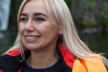 Fototapeta premium Close-up face of an adult blonde girl smiling with wrinkles appearing and her gaze is directed to the side with hope in her eyes alone.