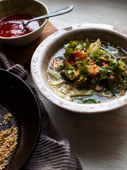 Asian vegetable soup with roasted sesame and hot sauce in natural light.
