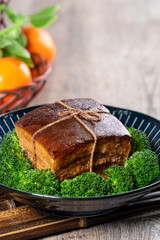 Dong Po Rou (Dongpo pork meat) in a beautiful blue plate with green broccoli vegetable, traditional festive food for Chinese new year cuisine meal, close up.