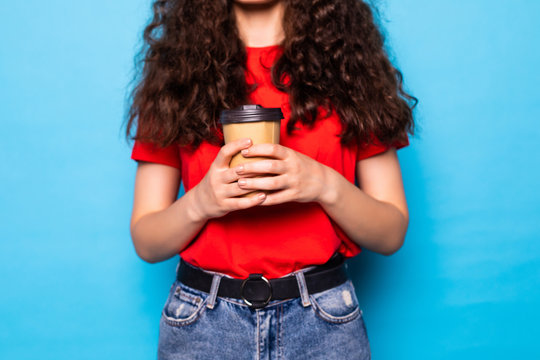 Young Pretty Woman Holds Takeout Coffee Stands Over Blue Wall.