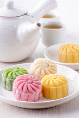Obraz na płótnie Canvas Colorful snow skin moon cake, sweet snowy mooncake, traditional savory dessert for Mid-Autumn Festival on bright wooden background, close up, lifestyle.