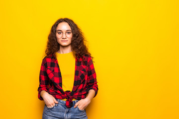 Smiling brunette woman posing with crossed arms over yellow background