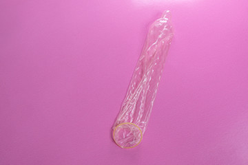 Latex condom on pink background