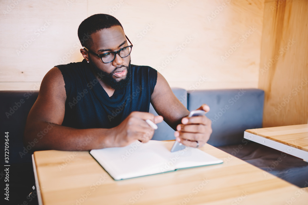 Poster serious african american hipster guy red information from networks via smartphone making planning in