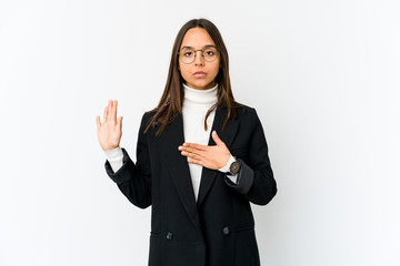 Young mixed race business woman isolated on white background taking an oath, putting hand on chest.