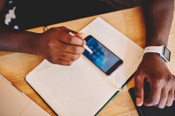 Cropped image of dark skinned man unlock security code on smartphone using stylus, african american...