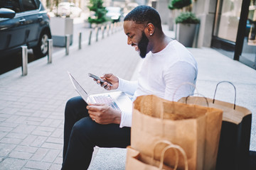 Cheerful african american hipster guy happy about getting discount on email for shopping in web...