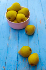 Ripe pears from the city garden lie on a wooden table and in a plate