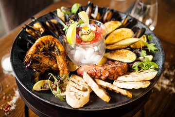 Seafood platter for 2-4 persons. Octopus, blue mussels, cooked green mussels, grilled tiger prawns, tuna tartare. Delicious seafood closeup served on a table for lunch in modern gourmet restaurant