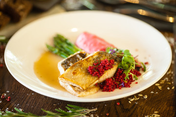 Pike-perch fillet. Asparagus, pearl couscous, white wine sauce, beet-flavored mashed potatoes. Delicious seafood fish closeup served on a table for lunch in modern cuisine gourmet restaurant
