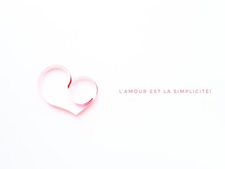 The heart is made of red paper on a white background. Text Love is simplicity in English . Valentine's Day.