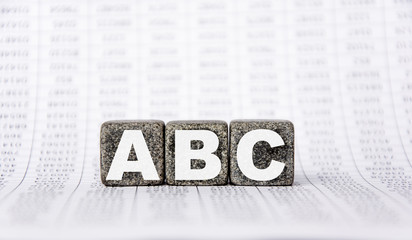 three stone cubes on the background of white financial statements, tables with the word ABC. Strong business concept