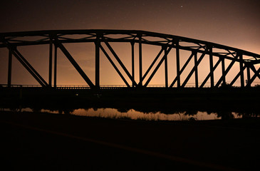 Railway bridge on river in colourful night