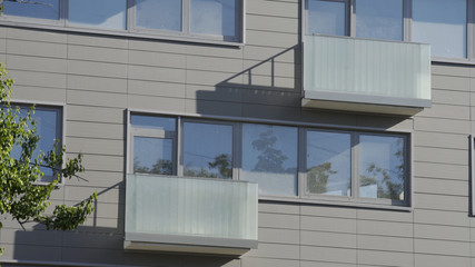 Close up shot of residential building. Apartment building exterior with reflection in windows. The building features exterior with small balconies