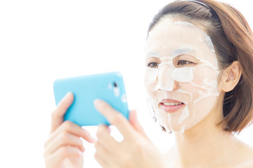 フェィスパックしてスマホを見る女性