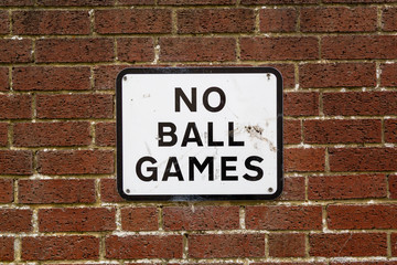 A No ball games sign on a brick wall on the side of a property