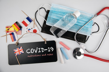 COVID-19 restrictions and rules. Medical masks, hand sanitizer and stethoscope. Chalk board and...