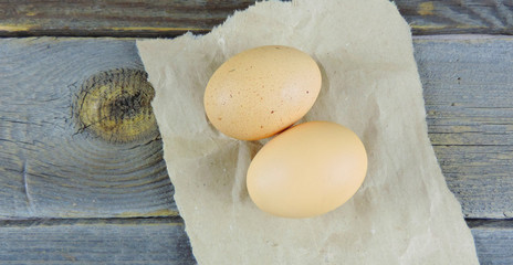 two brown eggs on craft paper on a wooden surface