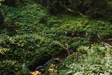 Silhouettes of a group of people with backpacks walking on a mountain road. Tourism concept