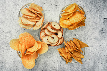 Potato and corn chips, snacks, crackers in transparent glass plates and sauces. Mix of snacks.