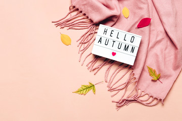 Lightbox with Hello Autumn text on pastel background. Cozy draped scarf and leaves