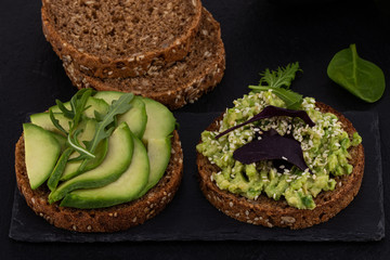 Avocado sandwich on dark rye bread on a dark background