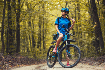 Fototapeta na wymiar Caucasian woman cyclist rides mountain bike forest trails. leisure