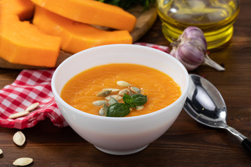 Pumpkin and carrot soup with pumpkin seeds on wooden background