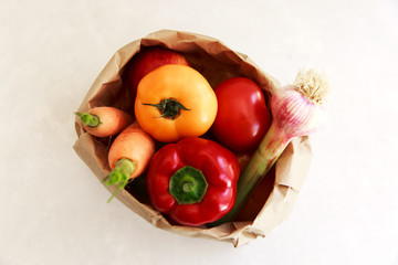 Paper grocery bag with fruits and vegetables over white background, eco shopping, zero waste, vegetarian concept