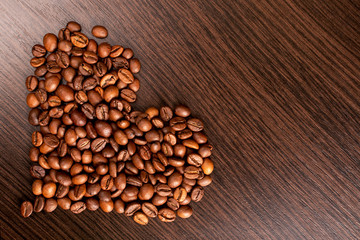 Heart shape made from coffee beans. Roasted Coffee beans background close up. International coffee day concept.