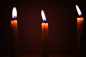 White Candles Burning in the Dark with lights glow, the burning candle's flame in the dark background, a symbol of the Christian faith, Candles burning in the Dark with lights glow