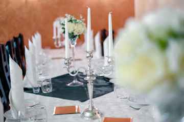 Silver candlestick with white candles on a decorated table.