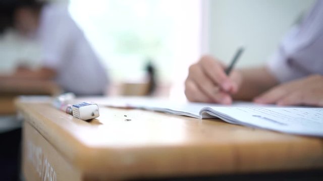 Student hand testing doing test exam with pencil drawing selected choices on answer sheet in school final exams at college or university. Taking multiple choice for assessment in examination classroom