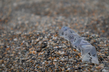 Clear set of Dungeon and Dragons dice with character sheets at the beach