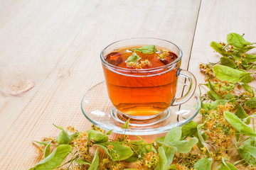 Lime blossom tea in a transparent cup on a wooden table
