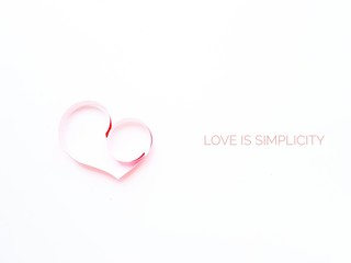 The heart is made of red paper on a white background. Text Love is simplicity in English. Valentine's Day.