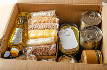 Set of uncooked foods in carton box prepared for disaster emergency conditions or giving away closeup view - obrazy, fototapety, plakaty