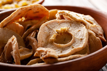 Dehydrated dried apples in clay bowl on wooden kitchen table food background