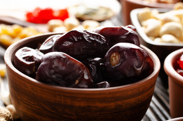Dehydrated dried dates in clay bowl on wooden kitchen table food background