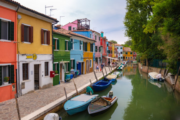 Naklejka na ściany i meble Burano, Italy - 09-18-2019 Colorful houses by canal in Burano, Italy. Burano is an island in the Venetian Lagoon and is known for its lace work and brightly colored homes.