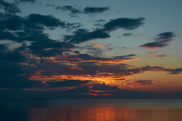 Baltic evening sea. Orange sunset, sun in the clouds. Sea twilight in the amber color of sunbeams.