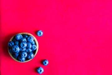 Blueberries in wooden bowl on the red background. top view