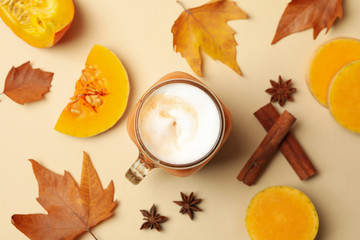Composition with pumpkin latte, pumpkin, leaves and cinnamon on beige background