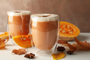 Composition with pumpkin latte, cinnamon, leaves and pumpkin on white wooden table