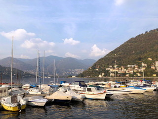 Fototapeta na wymiar Yachts and boats at the marina - travelling Como Lake, Italy. Hills, mountains and water. Soft sunset. Mobile photo