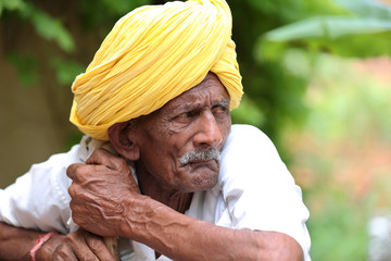 Amazed old Indian man wearing yellow turban looking up with mouth opened. Curious old man. Wearing...