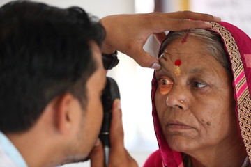 Old Indian woman in pink mantilla from Rajasthan getting eyes tested. Eye camp. Eye patient. Weak...