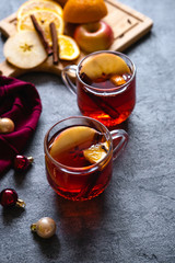 Mulled wine hot drink with citrus, apple and spices  on concrete background.